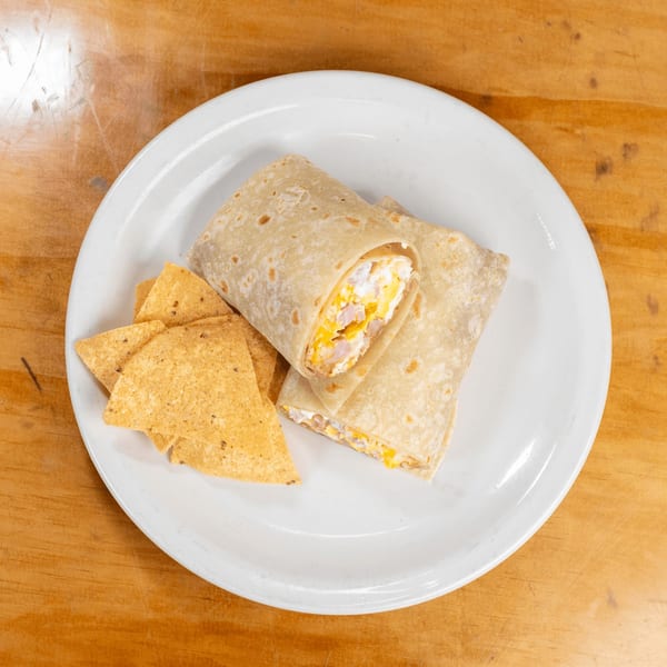 Two breakfast burritos filled with eggs and cheese, served with tortilla chips on a white plate.