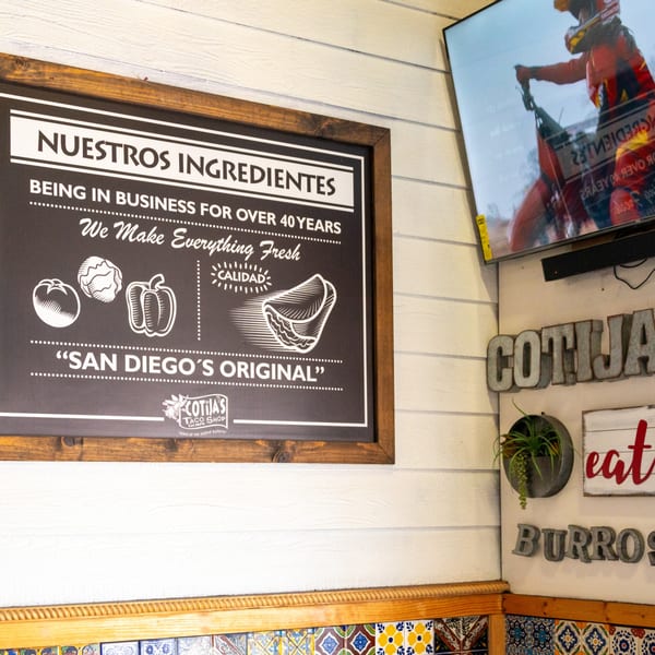 Cotijas Taco Shop interior with a sign about fresh ingredients and a TV showing a dirt bike.