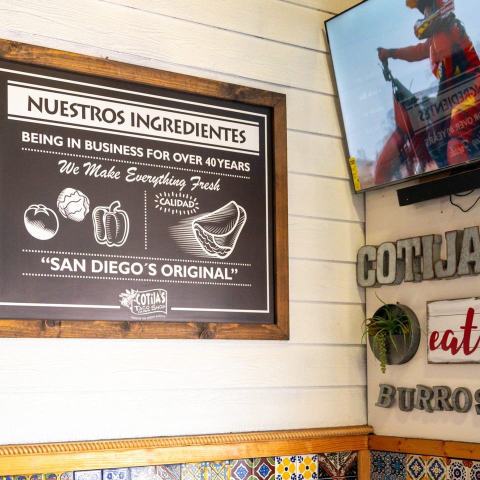 Cotijas Taco Shop interior with a sign about fresh ingredients and a TV showing a dirt bike.
