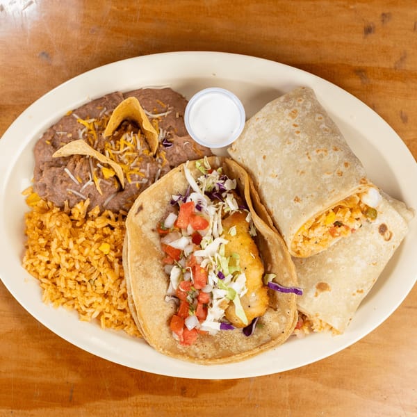 A Mexican combo plate with a fish taco, burrito, refried beans, rice, and sour cream.